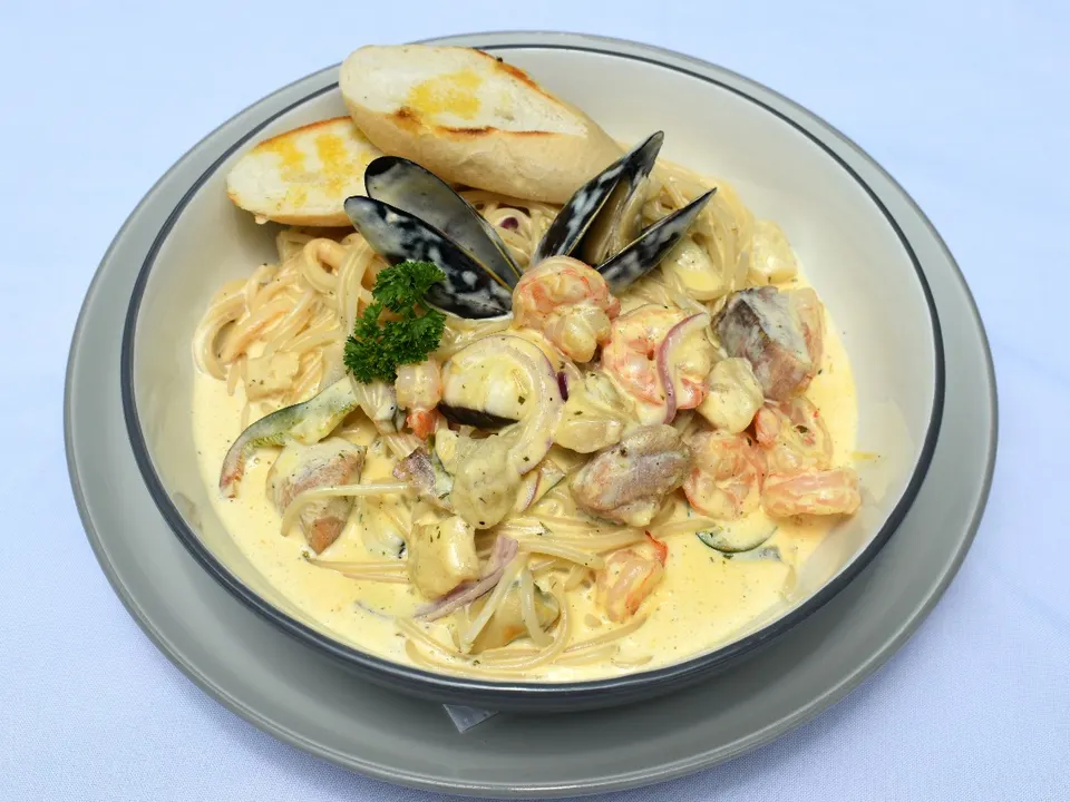 Pasta con camarones y mejillones en salsa blanca con pan tostado