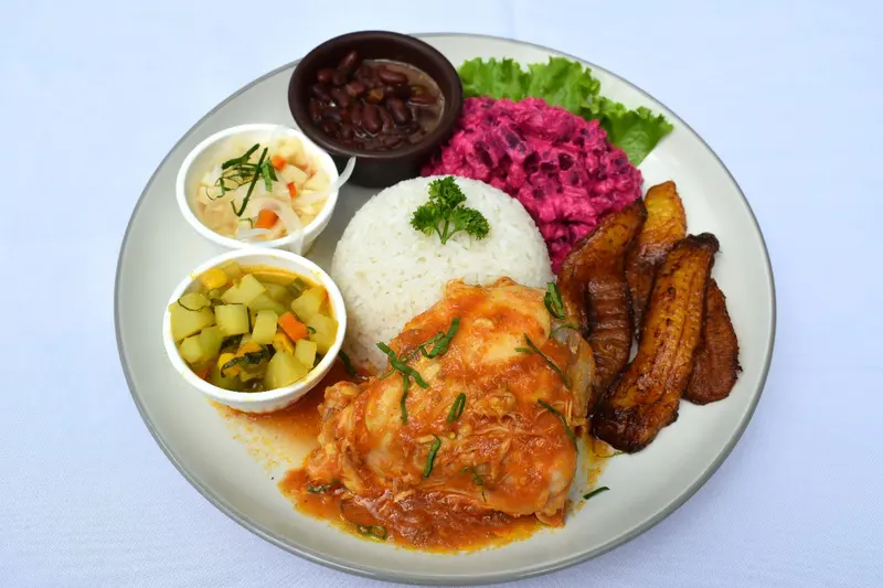 Pollo en salsa roja con arroz blanco, ensalada de remolacha y plátano maduro